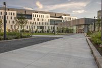 the walkway has white benches in front of it to the side of a building with several windows