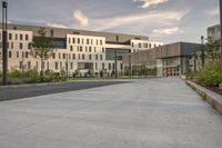 the walkway has white benches in front of it to the side of a building with several windows