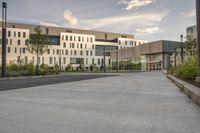 the walkway has white benches in front of it to the side of a building with several windows