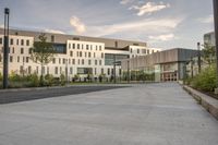 the walkway has white benches in front of it to the side of a building with several windows