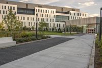 the walkway has white benches in front of it to the side of a building with several windows