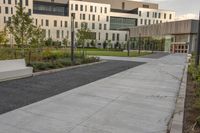 the walkway has white benches in front of it to the side of a building with several windows