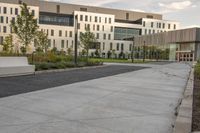 the walkway has white benches in front of it to the side of a building with several windows