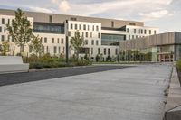 the walkway has white benches in front of it to the side of a building with several windows