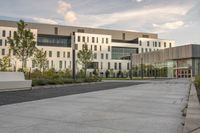 the walkway has white benches in front of it to the side of a building with several windows