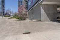 the sidewalk near an industrial building with a bench in the corner of it and a bench on a street outside