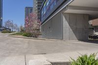 the sidewalk near an industrial building with a bench in the corner of it and a bench on a street outside