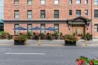 a couple of tables in front of a brick building and large patio umbrellas over it