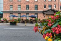 a couple of tables in front of a brick building and large patio umbrellas over it