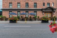 a couple of tables in front of a brick building and large patio umbrellas over it