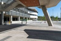 a sidewalk with benches that are under a large bridge to the right of the walkway is a metal frame with concrete columns