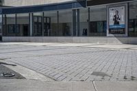 a person sitting at the bench in front of a mall that is empty of people