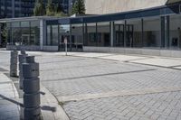 a person sitting at the bench in front of a mall that is empty of people