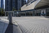 a person sitting at the bench in front of a mall that is empty of people