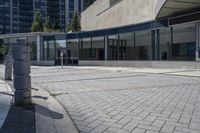 a person sitting at the bench in front of a mall that is empty of people