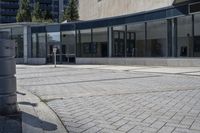 a person sitting at the bench in front of a mall that is empty of people