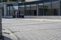 a person sitting at the bench in front of a mall that is empty of people