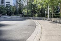 a car driving down an empty street lined with tall buildings and trees in the background