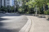 a car driving down an empty street lined with tall buildings and trees in the background