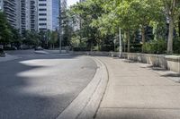 a car driving down an empty street lined with tall buildings and trees in the background