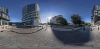 a fisheye lens on a city square with buildings in the background and a few people walking