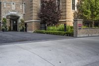 a city street filled with a stone and brick building next to a sidewalk and trees