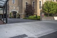 a city street filled with a stone and brick building next to a sidewalk and trees