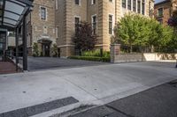 a city street filled with a stone and brick building next to a sidewalk and trees