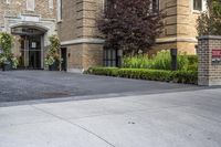 a city street filled with a stone and brick building next to a sidewalk and trees