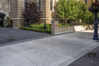 a city street filled with a stone and brick building next to a sidewalk and trees