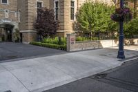 a city street filled with a stone and brick building next to a sidewalk and trees