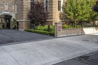 a city street filled with a stone and brick building next to a sidewalk and trees