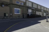 a person on a skateboard in the street in front of an industrial building with a banner