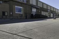 a person on a skateboard in the street in front of an industrial building with a banner