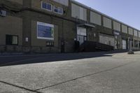 a person on a skateboard in the street in front of an industrial building with a banner