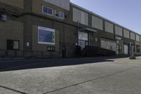 a person on a skateboard in the street in front of an industrial building with a banner