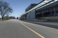 a empty street and a big building that is next to it with trees in the front