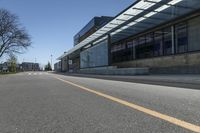 a empty street and a big building that is next to it with trees in the front