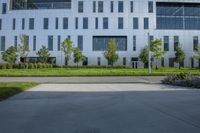 a gray concrete plaza is full of trees and bushes with white building in the background