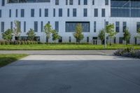 a gray concrete plaza is full of trees and bushes with white building in the background