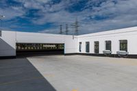 the empty building has three windows and doors near it's parking area on the outside