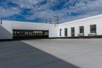 the empty building has three windows and doors near it's parking area on the outside