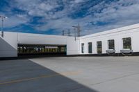 the empty building has three windows and doors near it's parking area on the outside