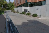 an empty concrete path with a metal fence and building in the background from the bottom