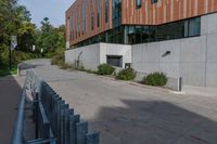 an empty concrete path with a metal fence and building in the background from the bottom