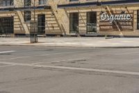 a building that says organic in front of it and there is an empty parking space to the side with cars