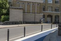 there is a parking meter near an empty street with buildings on the other side of the road