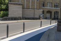 there is a parking meter near an empty street with buildings on the other side of the road