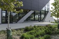 an empty courtyard near some plants and trees with large windows on top of the building