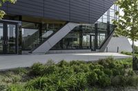 an empty courtyard near some plants and trees with large windows on top of the building